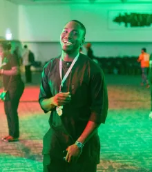 A guest laughing under the green lights of the after party.