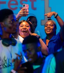 The crowd filming the stage with their phones up, under blue light.