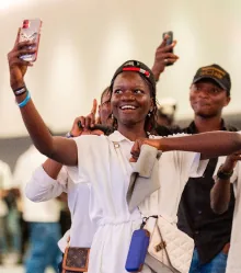 A guest in white cheering with both arms raised.